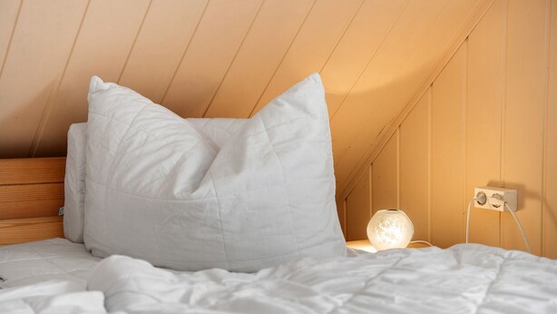 A bedroom with a wooden headboard, white bedding, and a bedside table with a lamp. - Apartment 'Am Darß - Kogge' with Private Terrace, Private Garden and Wi-Fi (Pruchten)
