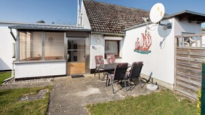 A house with a satellite dish, a dining area with chairs, and a ship mural on the wall. - Apartment 'Am Darß - Kogge' with Private Terrace, Private Garden and Wi-Fi (Pruchten)