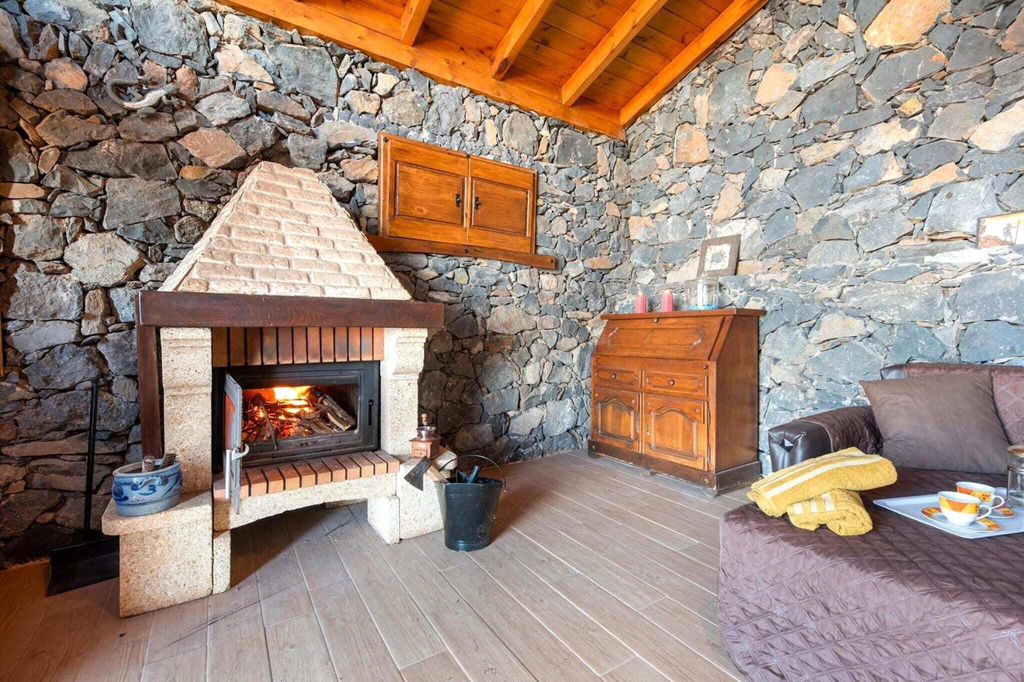 A stone-walled room with a fireplace, wooden cabinets, and a cozy seating area.