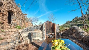 A rustic stone wall with a wooden bench and a table with lemons and oranges.