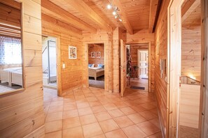 Interior de uma cabana de madeira com quarto, banheiro e cozinha.