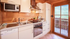 A compact kitchen with a microwave, stove, sink, and a window overlooking a garden.