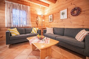 A cozy log cabin interior with two grey sofas, a wooden coffee table, and a floor lamp.
