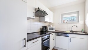 Una cocina moderna con armarios blancos, encimera negra, horno integrado, microondas y ventana con vistas.
