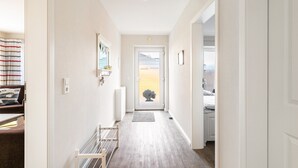 A hallway with a door at the end, a radiator, a small rug, and a shelf with items. - Apartment 'Stine' with Shared Terrace, Shared Garden and Wi-Fi (Breklum)