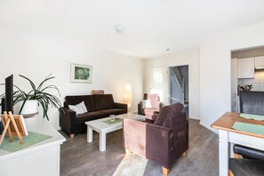 Ein modernes Wohnzimmer mit einer Couch, Sesseln, einem Couchtisch und einem Essbereich.