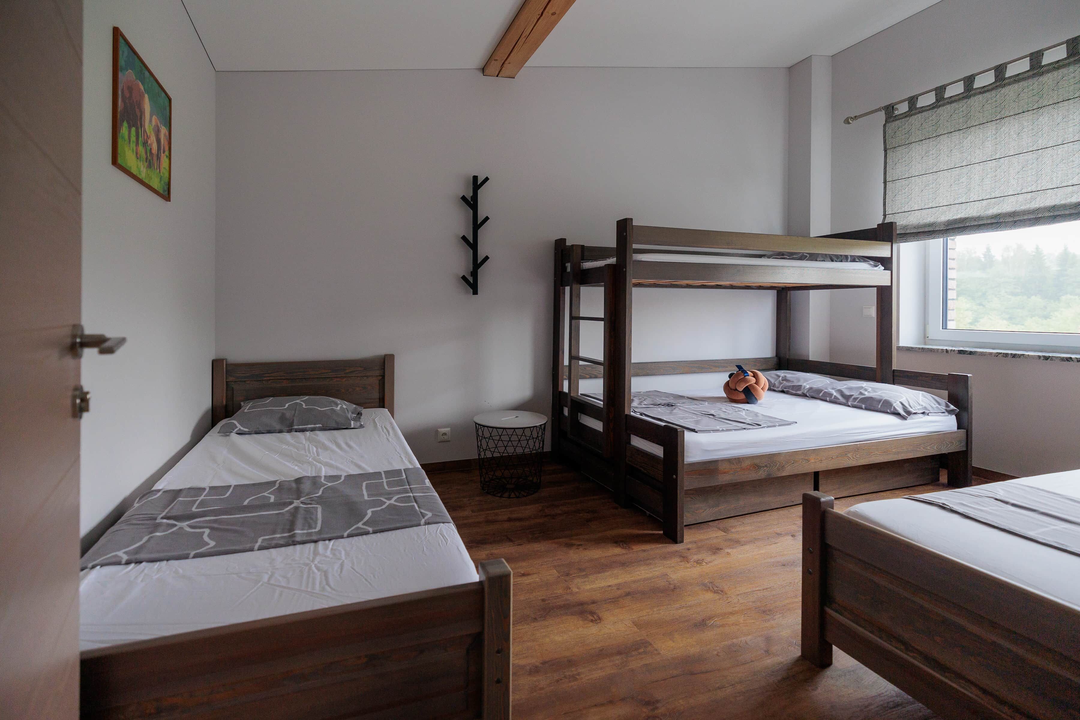 A room with two bunk beds, a small round table, and a window with a view.