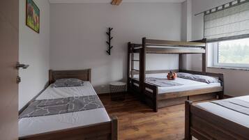 A room with two bunk beds, a small round table, and a window with a view.