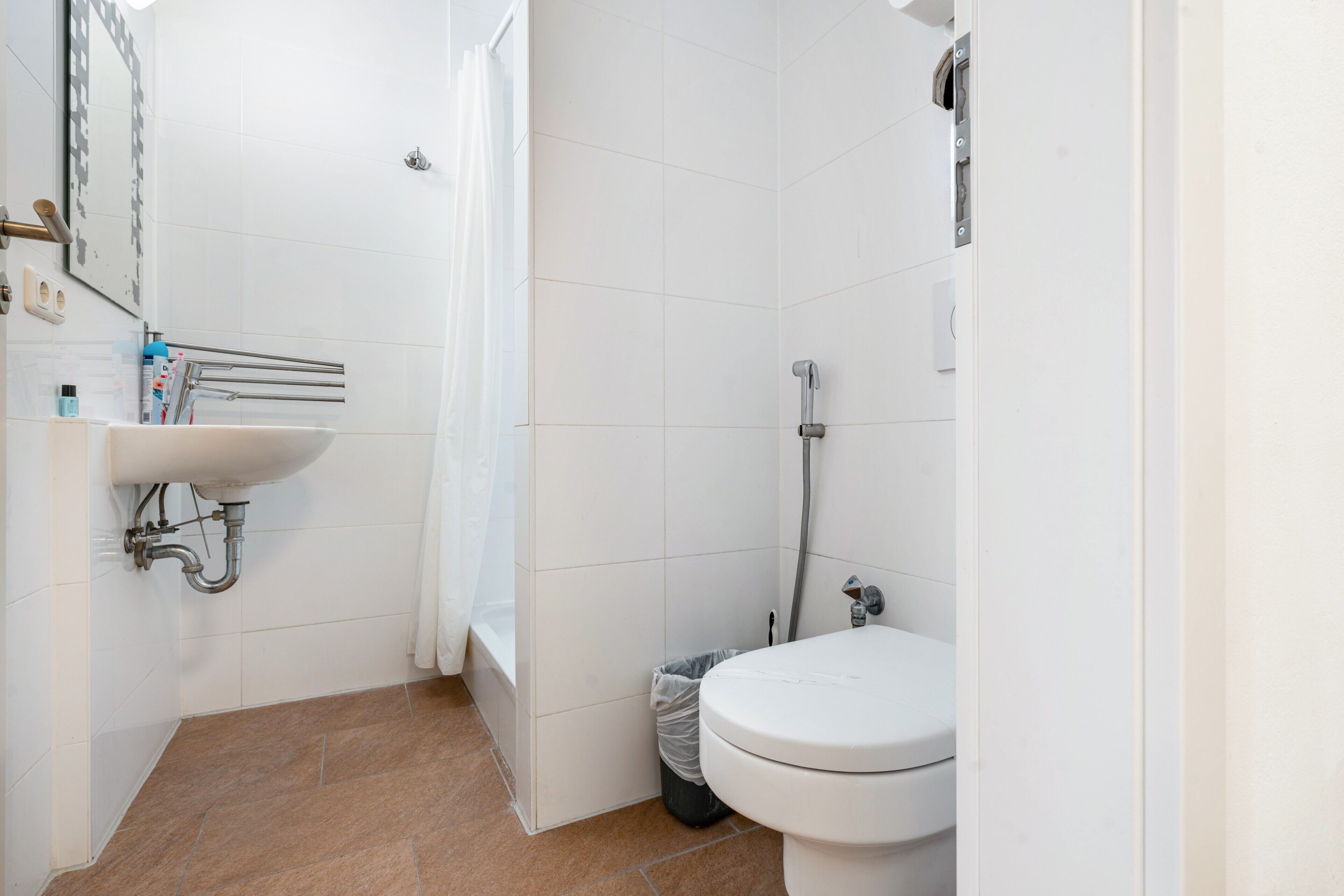 Un bagno con lavandino, WC, doccia e pavimento piastrellato.