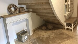 A staircase with a wooden finish, a white wall, and a small bench.