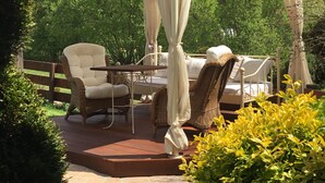 A gazebo with a table and chairs, surrounded by greenery.