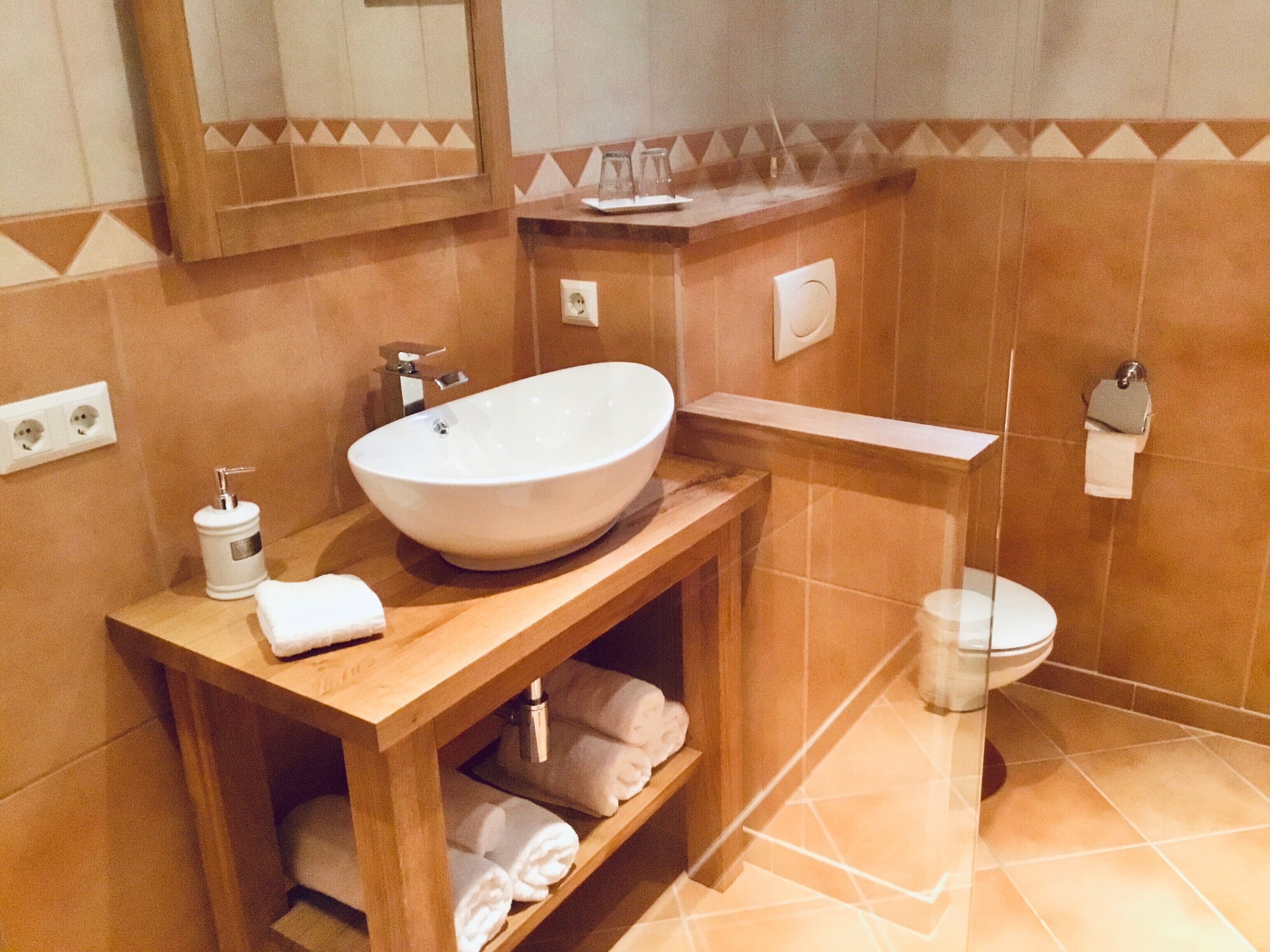 A bathroom with a large vessel sink, a mirror, a towel rack, and a toilet.