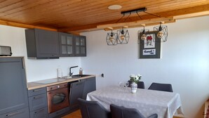Une cuisine moderne avec des meubles gris, un plan de travail en bois et un coin repas comprenant une table et des chaises.