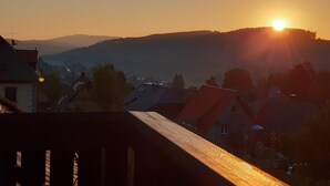 Un coucher de soleil sur une zone résidentielle, avec des maisons et une montagne en arrière-plan.