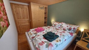 Une chambre à coucher avec un lit, une armoire en bois et un mur vert.