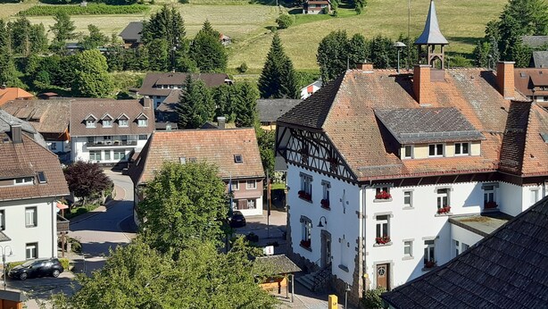 Un village à l’architecture traditionnelle, une église et une colline surmontée d’une croix.