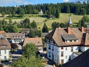 A village with traditional architecture, a church, and a hill with a cross.