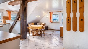 Zona pranzo con tavolo e sedie in legno, una scala e vista sull'esterno.
