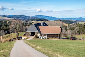 Une maison de campagne avec une allée pavée, un garage et un grand terrain découvert.