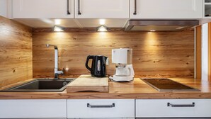 A modern kitchen with wooden cabinetry, a sink, a kettle, a coffee maker, and a cutting board. - Apartment '2- Ost' with Private Garden, Balcony and Wi-Fi (Sankt Märgen)