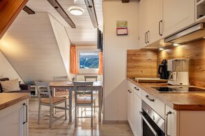 Une cuisine moderne avec des plans de travail en bois, un coin repas avec une table et des chaises, et une fenêtre avec des rideaux.
