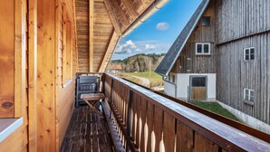 A wooden balcony with a view of a rural landscape and a large barn. - Apartment '2- Ost' with Private Garden, Balcony and Wi-Fi (Sankt Märgen)