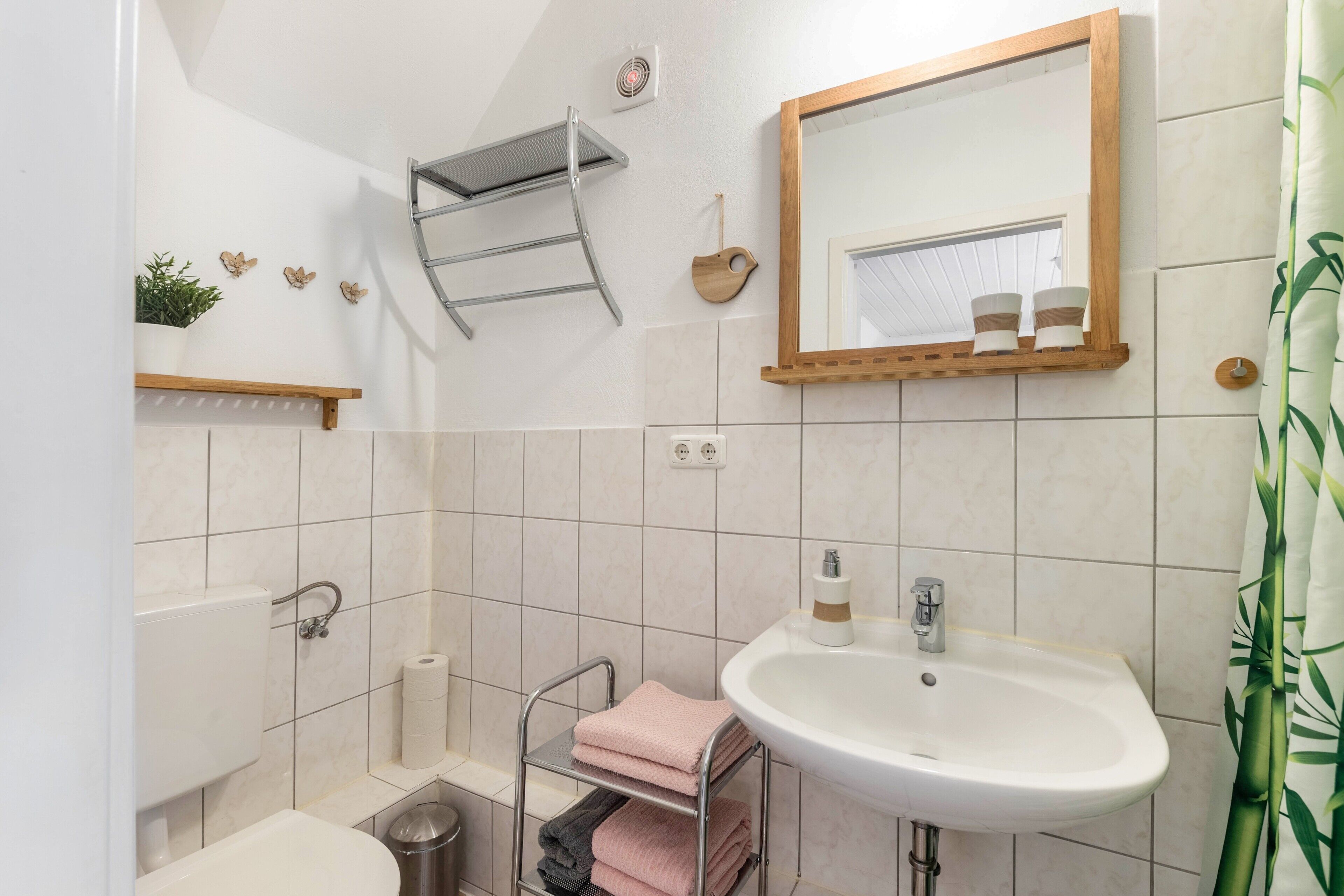 Een badkamer met een wastafel, spiegel, handdoekhouder en toilet.