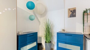 A bathroom with two blue cabinets, a potted plant, and paper lanterns on the ceiling.