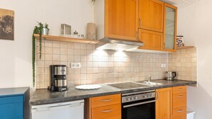 A kitchen with wooden cabinets, a dishwasher, a stove, and a coffee maker.