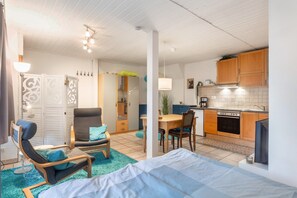 Um espaço compacto com cama, sofá, mesa de jantar e cozinha compacta.