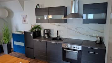 Une cuisine moderne avec des meubles de rangement aux couleurs sombres, un four encastré et une machine à café.