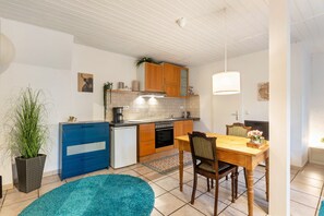 Uma cozinha compacta com armários de madeira, forno embutido e área de refeições com mesa e cadeiras de madeira.