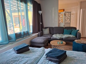 Un salon comprenant un canapé, un pouf et une petite table ronde agrémentée d’objets décoratifs.
