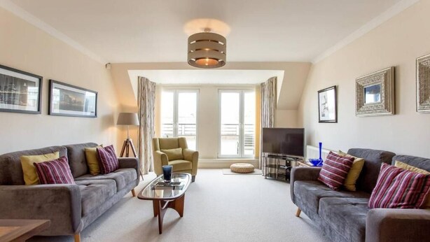 A living room with two sofas, a coffee table, a TV, and a lamp. - JOIVY Inviting Apartment near Leith Walk (Edinburgh)
