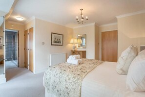 A bedroom with a large bed, a bedside lamp, a radiator, and a door leading to another room. - JOIVY Inviting Apartment near Leith Walk (Edinburgh)