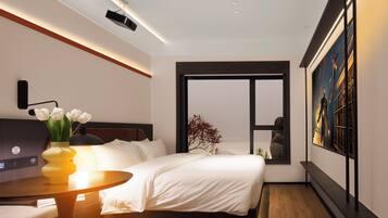 Una habitación de hotel moderna con cama, mesita de noche y un ventanal grande.