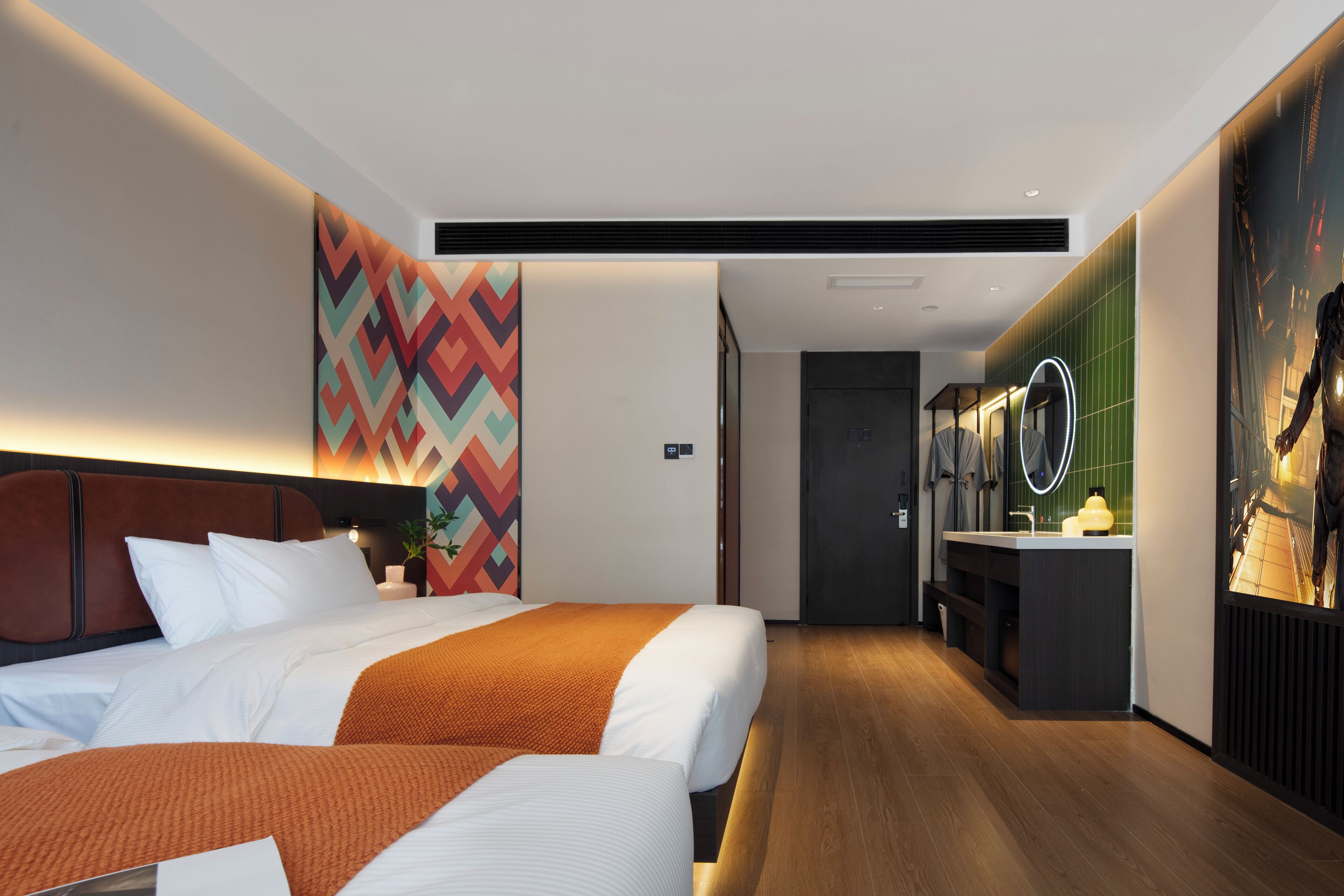 A modern hotel room with two beds, a bathroom with a mirror, and a hallway leading to another room.