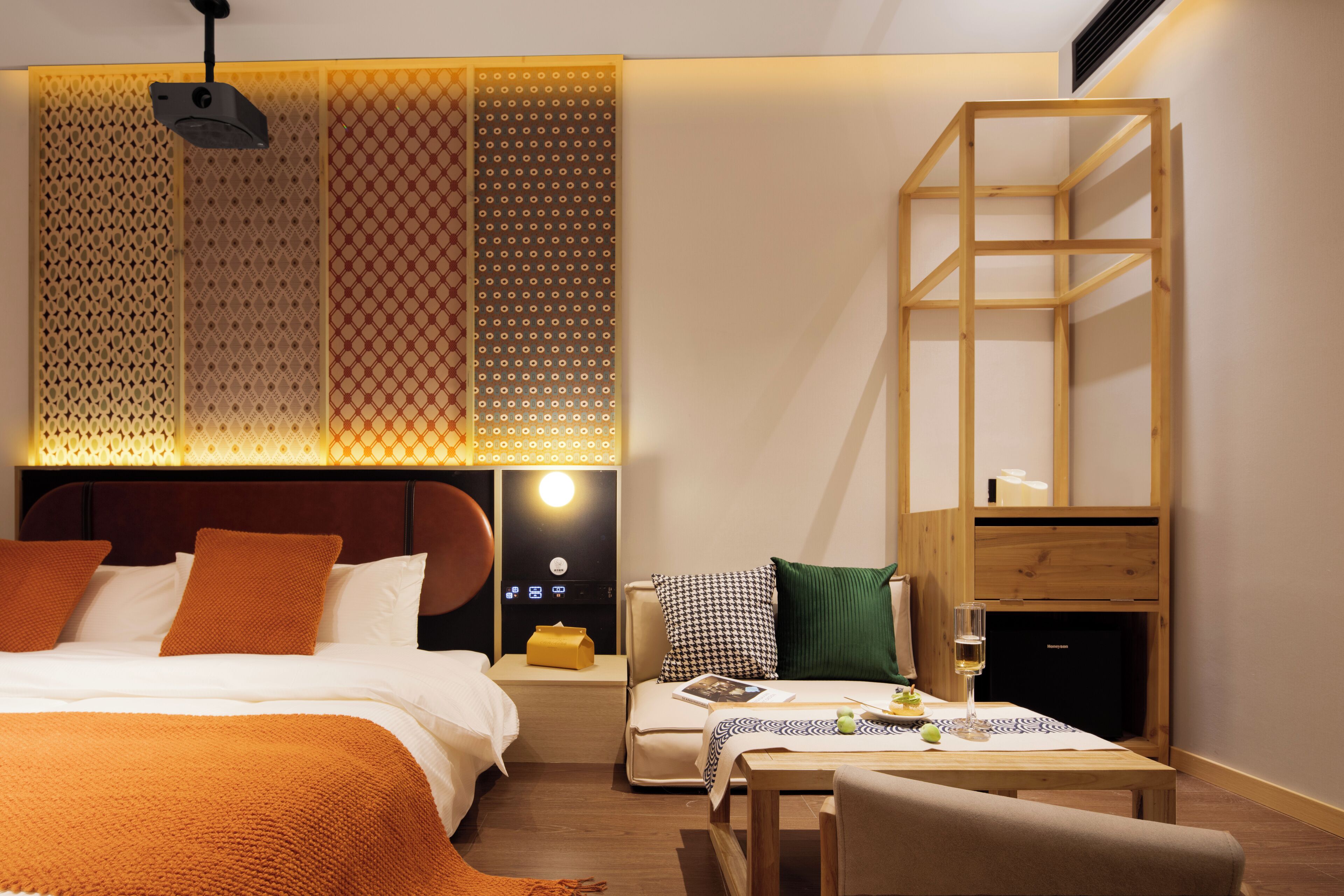 A modern hotel room with a bed, bedside table, and a small seating area with a table and chairs.