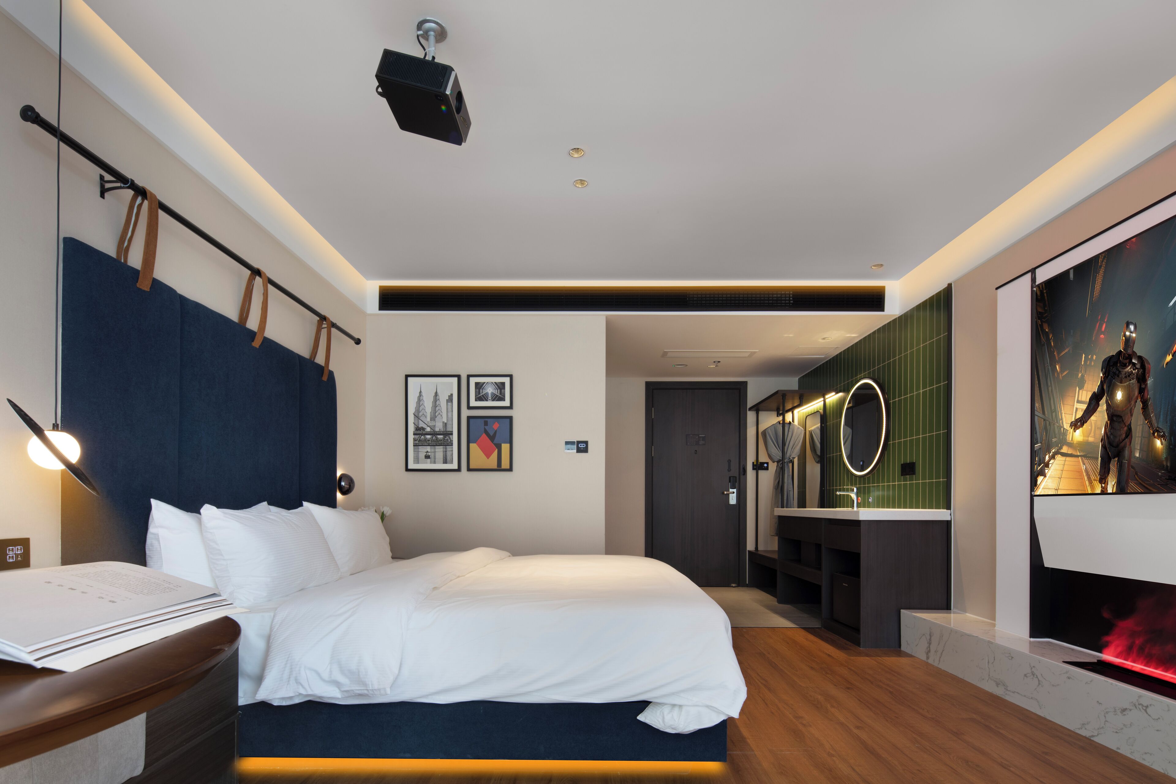 Ein modernes Hotelzimmer mit einem großen Bett, einem Schreibtisch, einem Schminktisch mit Spiegel und einem großen Bildschirm, der einen Film zeigt.