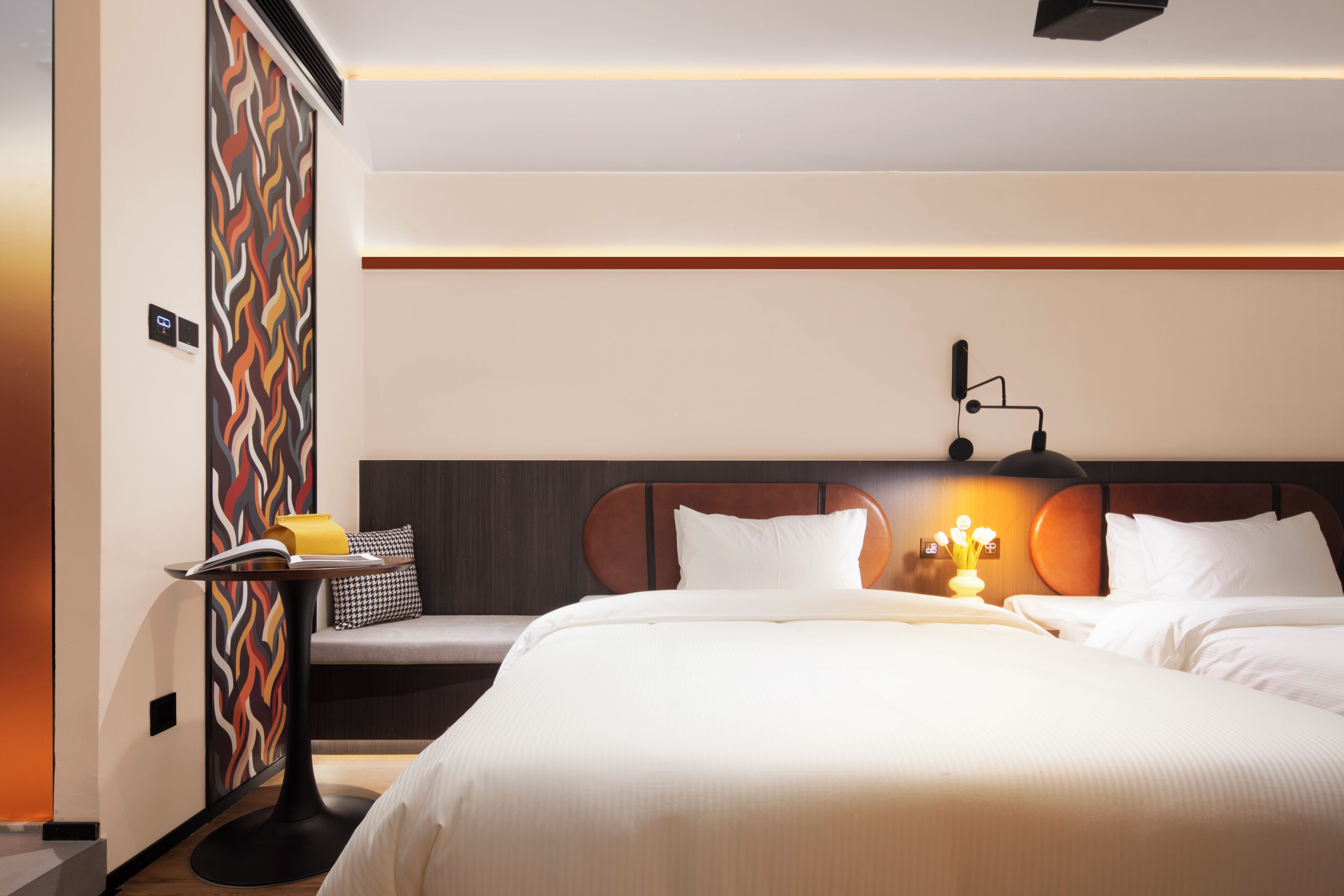 Habitación de hotel con una cama grande, mesita de noche, lámpara y un panel decorativo en la pared.