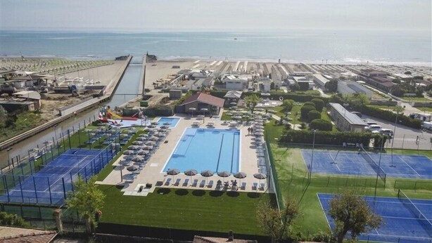 Um hotel à beira-mar com piscina, quadras de tênis e um porto de iates.