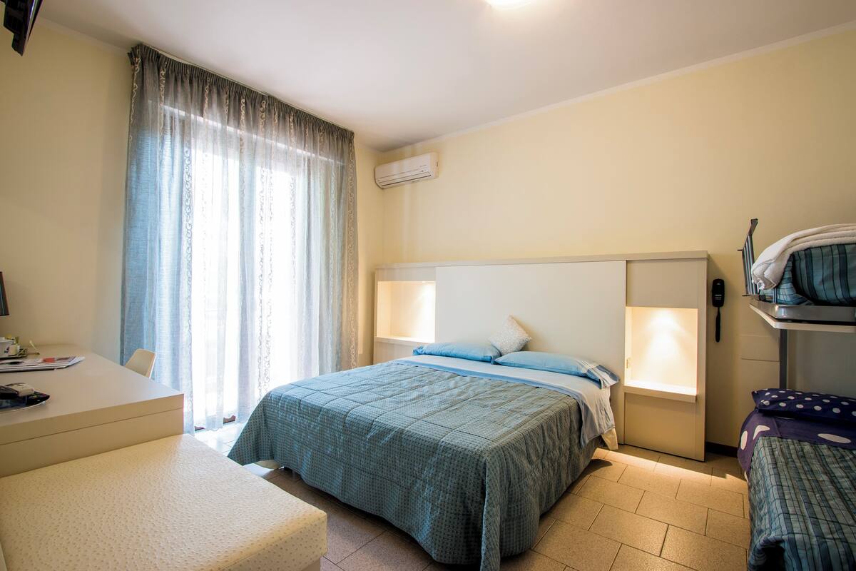 Hotellihuone, jossa on sänky, yöpöydät, työpöytä ja tuoli.