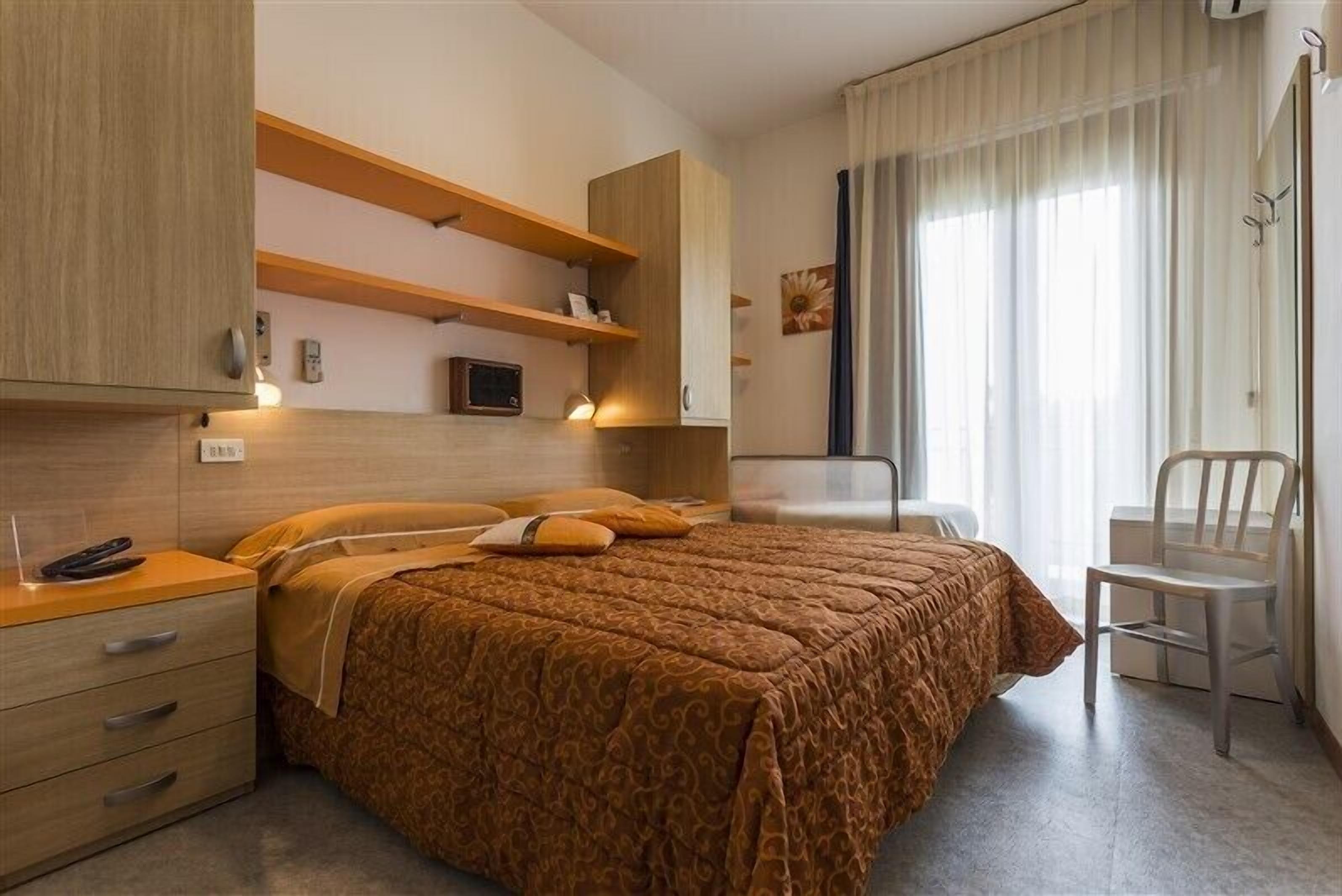 Ein Schlafzimmer mit einem Bett, Nachttischen, einem Sessel und integrierten Regalen.