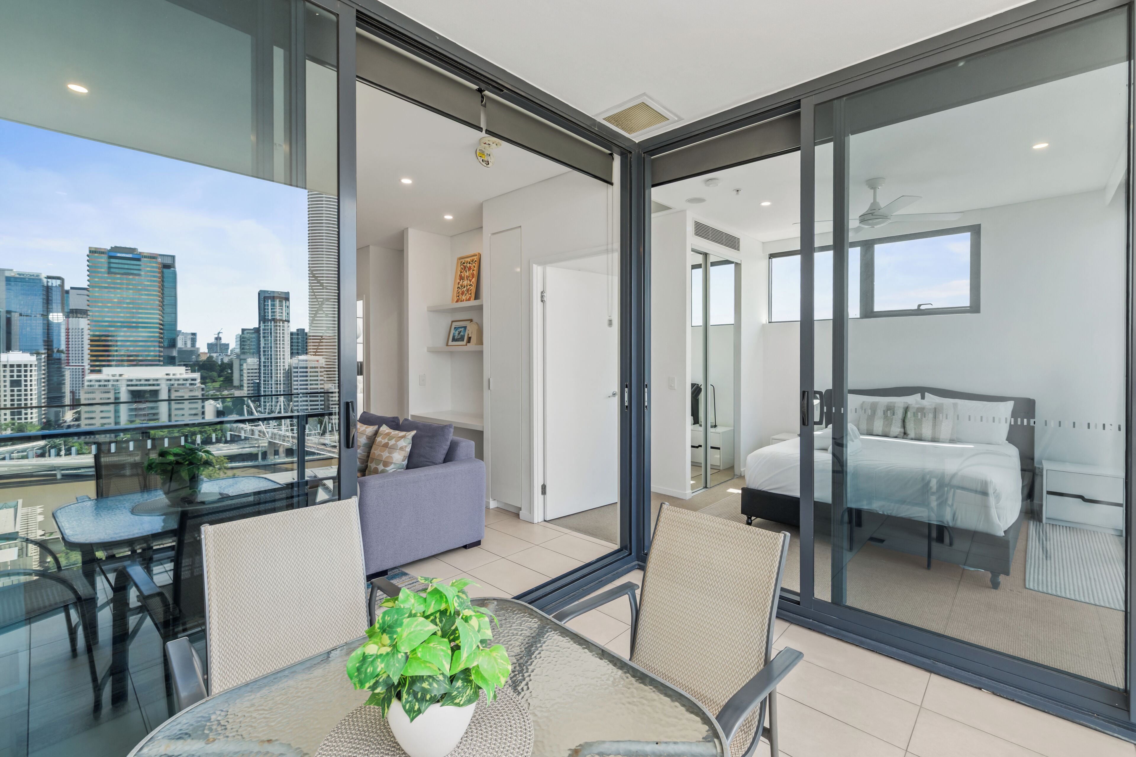 A modern apartment with a balcony, a dining area, a bedroom, and a living room.