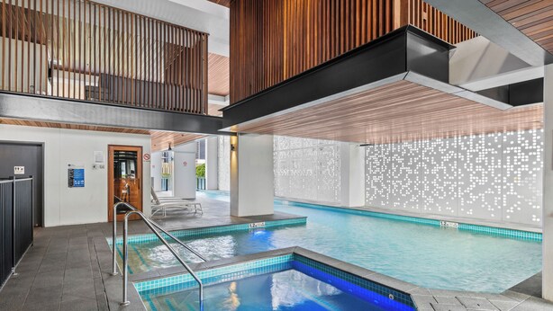 A swimming pool with a blue tint, a wooden ceiling, and a tiled wall with a light pattern. - Panorama river view with Free Parking (South Brisbane)