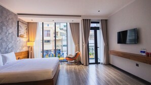 Ett hotellrum med en säng, en gungstol, en tv och utsikt över omgivningarna.