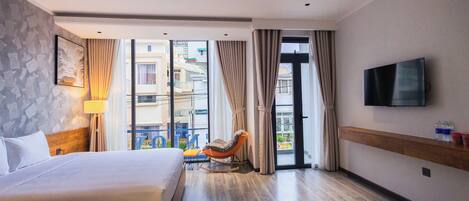 Ein Hotelzimmer mit Bett, Schaukelstuhl, Fernseher und Blick ins Freie.