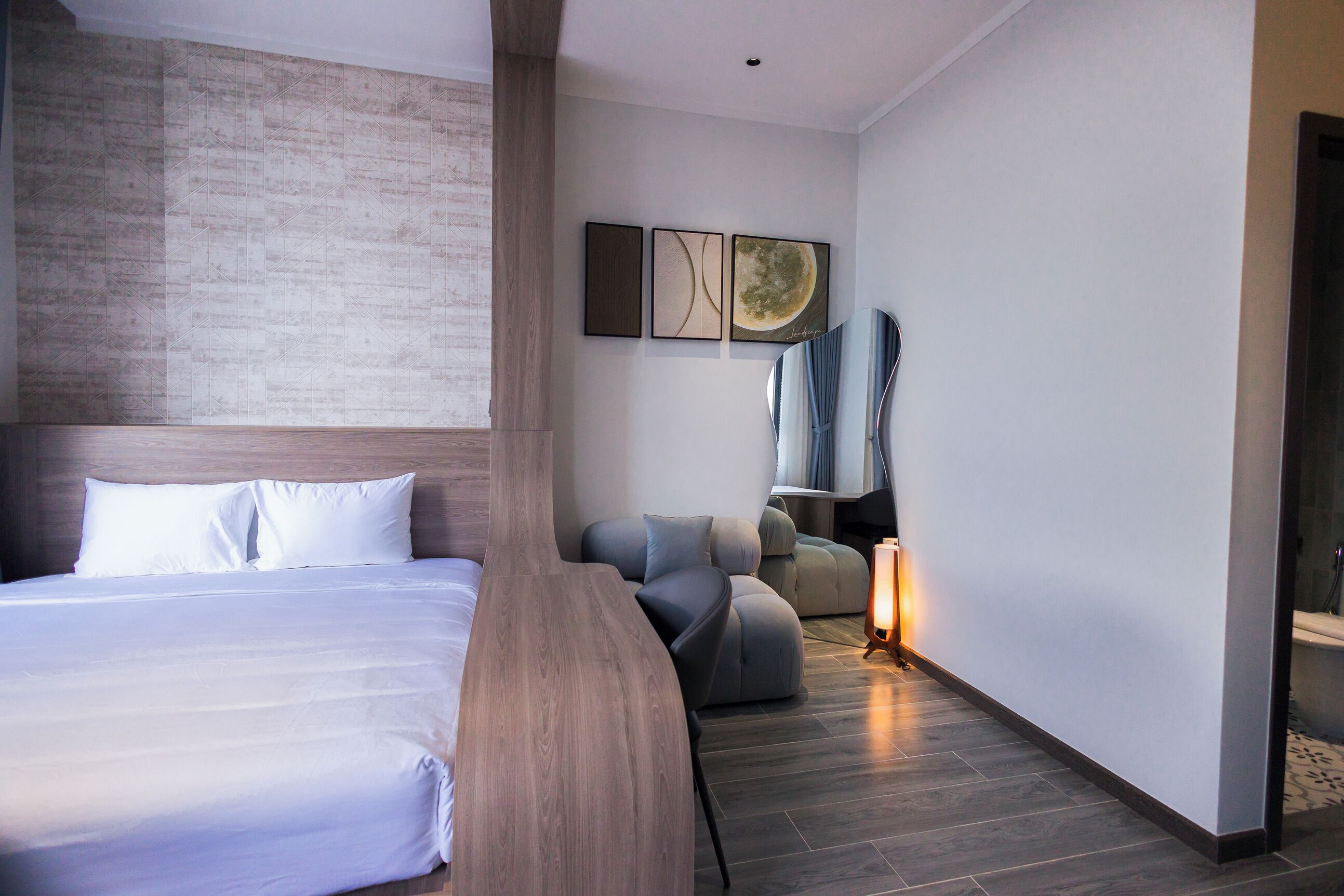 A modern hotel room with a large bed, a seating area, and artwork on the wall.