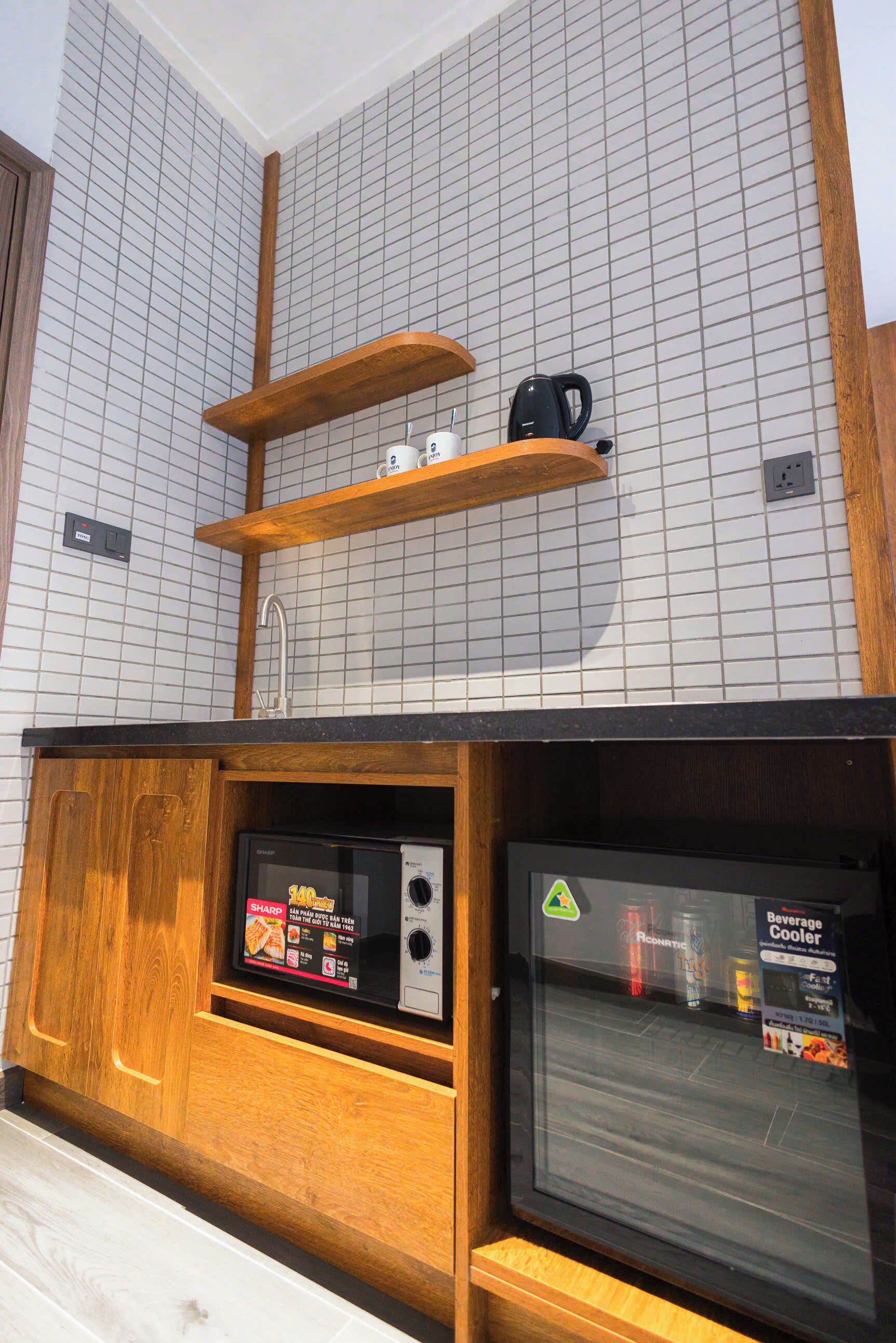 A kitchen with a microwave, a beverage cooler, and wooden shelves above the counter.