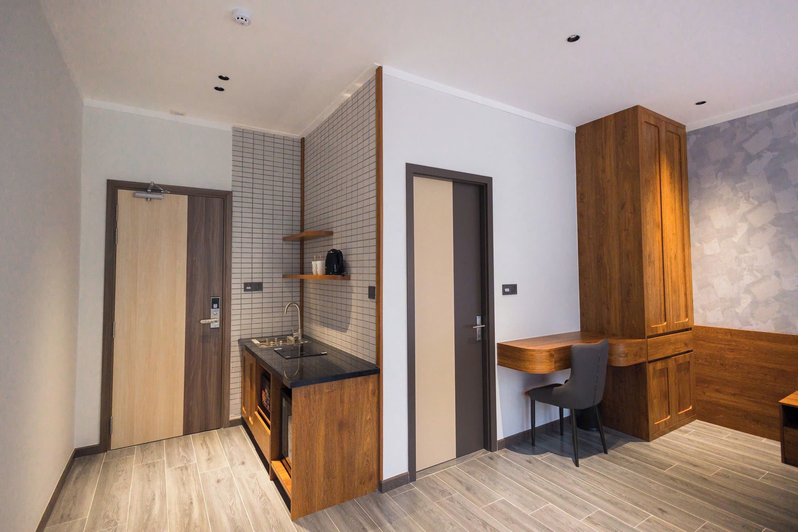 A compact kitchen with a wooden countertop, a sink, and a small dining area with a chair.